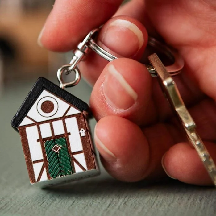 Handgefertigter Schlüsselanhänger aus Lindenholz im Design der Multiholk Fachwerkaus. Ein originelles Geschenk für Vogel-, Natur- und Skandinavienliebhaber.